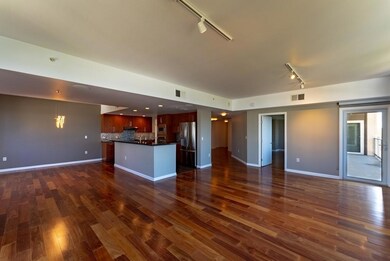 Unfurnished living room featuring track lighting and dark wood-style flooring