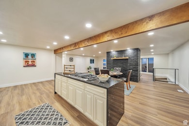 Kitchen with recessed lighting, cream cabinetry, a center island, dark stone countertops, and light wood-style floors