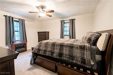 Carpeted bedroom with ceiling fan and a textured ceiling