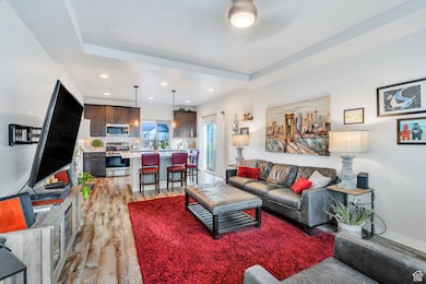 Living area with light wood-style flooring, recessed lighting, and a tray ceiling