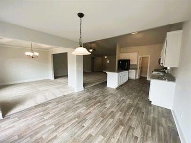 Kitchen featuring open floor plan, white cabinets, and dark wood finished floors