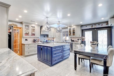 Kitchen featuring blue cabinetry, crown molding, recessed lighting, backsplash, and pendant lighting