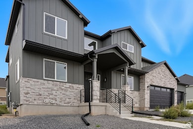 Modern farmhouse style home with board and batten siding, stone siding, and a garage