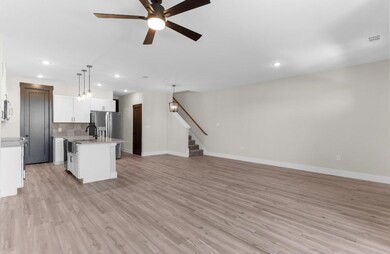 Kitchen featuring backsplash, a kitchen island with sink, pendant lighting, and light hardwood / wood-style floors