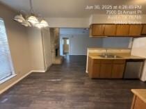 Kitchen with a chandelier, brown cabinetry, hangi