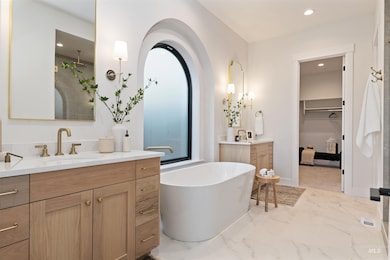 Full bathroom featuring a walk in closet, two vanities, light marble finish flooring, a stall shower, and recessed lighting