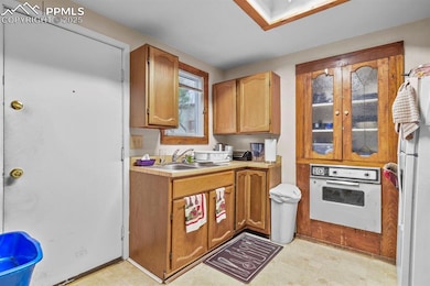 Kitchen featuring white appliances, light countertops, brown cabinetry, and a skylight
