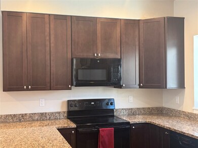 Kitchen with light stone counters, black appliance