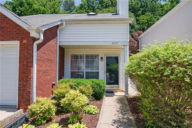 Doorway to property featuring a chimney, brick siding, a garage, and roof with shingles