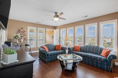 Living area featuring dark wood-style floors and a ceiling fan