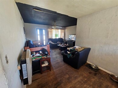 Living room with ceiling fan, a textured wall, woo