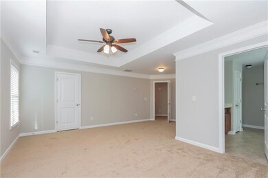 Spare room featuring a tray ceiling, ceiling fan, crown molding, and light carpet