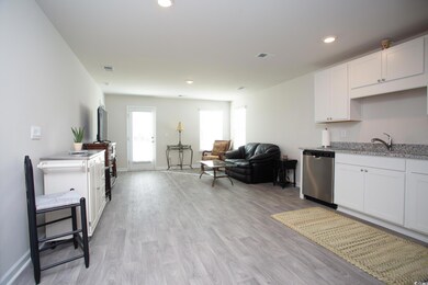 Kitchen featuring dishwasher, sink, light hardwood / wood-style floors, and white cabinets