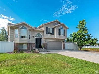 Bi-level home with a gate, a garage, brick siding, and concrete driveway