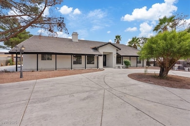 Ranch-style home with a tiled roof, curved driveway, stucco siding, and a chimney