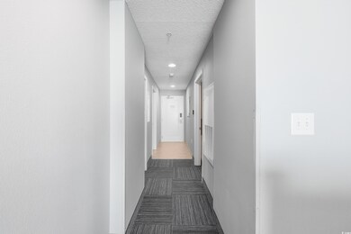 Corridor with dark carpet, a textured ceiling, and recessed lighting