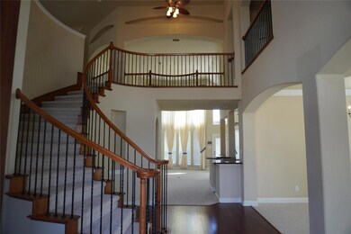 Entryway with ceiling fan, a towering ceiling, and hardwood / wood-style flooring