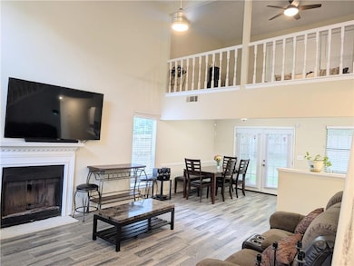 Two story lLiving area with ceiling fan, a high ceiling, wood finished floors, and healthy amount of natural light