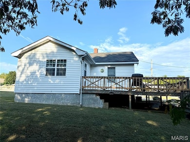 Rear view of property featuring a deck, a lawn, and a chimney