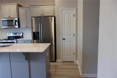 Kitchen with appliances with stainless steel finishes, light wood-style floors, a kitchen bar, light countertops, and backsplash