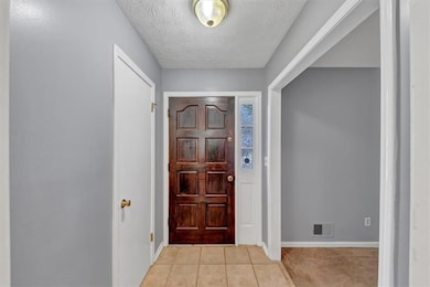 Entrance foyer with a textured ceiling and light tile patterned floors