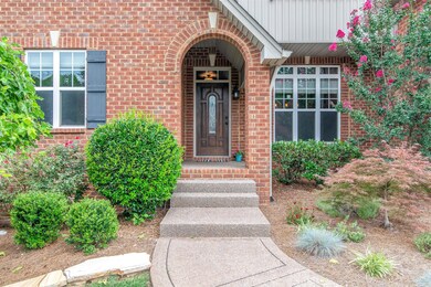 Covered arch entrance to home. Beautiful landscaping and home has common space to side and rear with view of pond