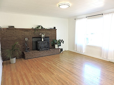 Unfurnished living room featuring a wood stove and wood-type finished floors