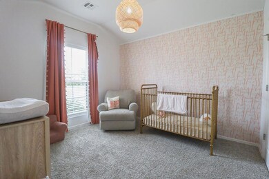 Carpeted bedroom with a nursery area, wallpapered walls, baseboards, and vaulted ceiling