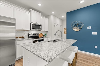 Kitchen with appliances with stainless steel finishes, backsplash, light stone countertops, light wood-style floors, and recessed lighting
