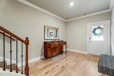 Foyer entrance with light wood-type flooring, ornamental molding, and stairs