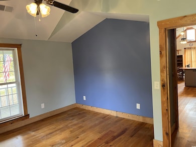 Spare room with ceiling fan, wood-type flooring, and lofted ceiling