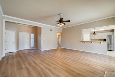 Living room with ceiling fan, light hardwood / wood-style floors, and crown molding