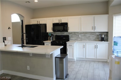 Kitchen featuring white cabinets, arched walkways,