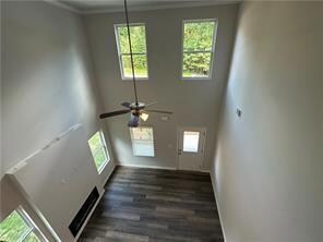 Unfurnished living room with plenty of natural light, wood finished floors, crown molding, and a ceiling fan