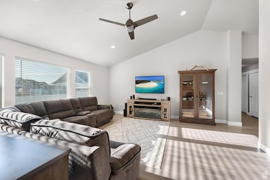 Living room with ceiling fan, wood finished floors, recessed lighting, and high vaulted ceiling