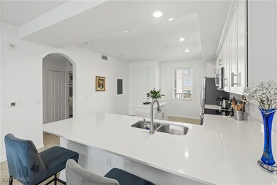 Kitchen with white cabinets, a peninsula, arched walkways, a kitchen bar, and recessed lighting