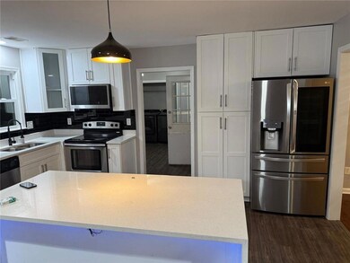 Kitchen featuring appliances with stainless steel finishes, separate washer and dryer, dark wood-style flooring, and white cabinets