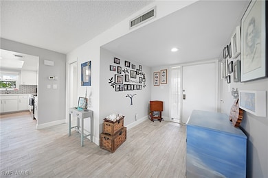 Foyer entrance with light wood-style floors, baseb