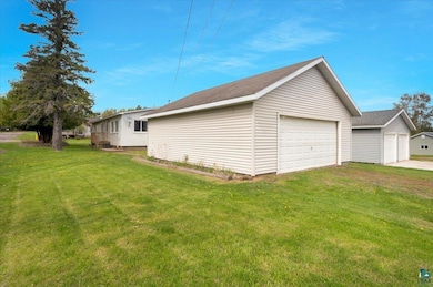 View of side of home with a garage, an outbuilding, and a yard