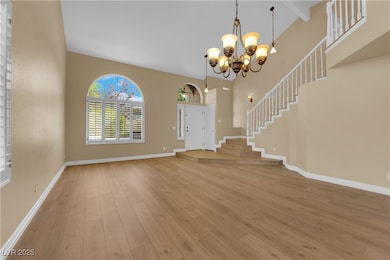 Entryway featuring light wood-type flooring, stairway, a chandelier, and a towering ceiling