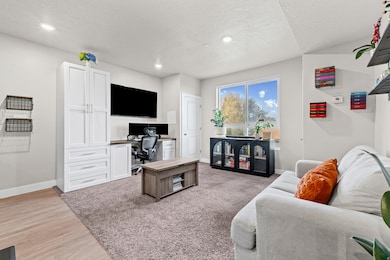 Living area with a desk, light wood finished floors, a textured ceiling, and recessed lighting