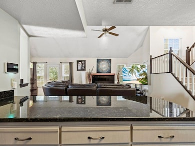 Kitchen with dark stone countertops, lofted ceiling, healthy amount of natural light, open floor plan, and a textured ceiling