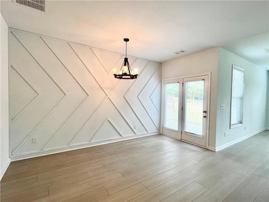 Unfurnished dining area featuring wood finished floors and a chandelier