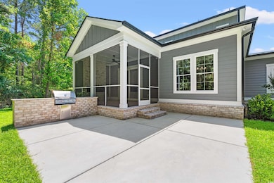 Back of house featuring a sunroom, board and batten siding, an outdoor kitchen, and a patio area
