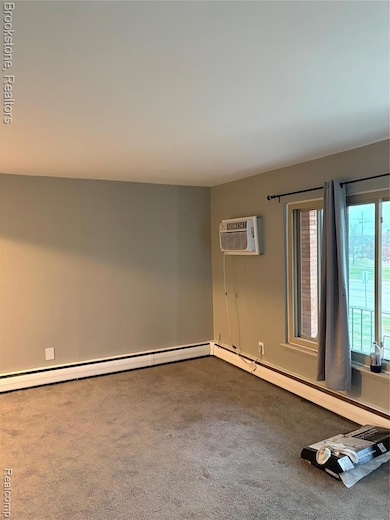 Carpeted spare room with a baseboard radiator and an AC wall unit