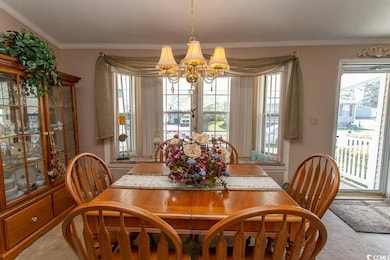 Dining room with plenty of natural light, carpet floors, a chandelier, and crown molding