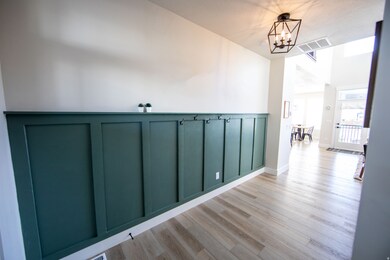 Hall with light wood-type flooring, a chandelier, and a decorative wall