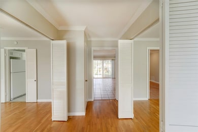 Hallway with light wood-style floors, crown moldi