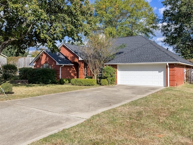 View of front of home featuring a shingled roof, concrete driveway, brick siding, a front yard, and a garage