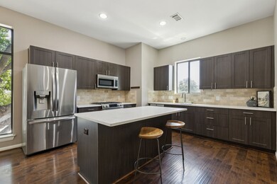 Kitchen featuring appliances with stainless steel finishes, dark brown cabinets, a kitchen island, a kitchen breakfast bar, and dark wood-style floors